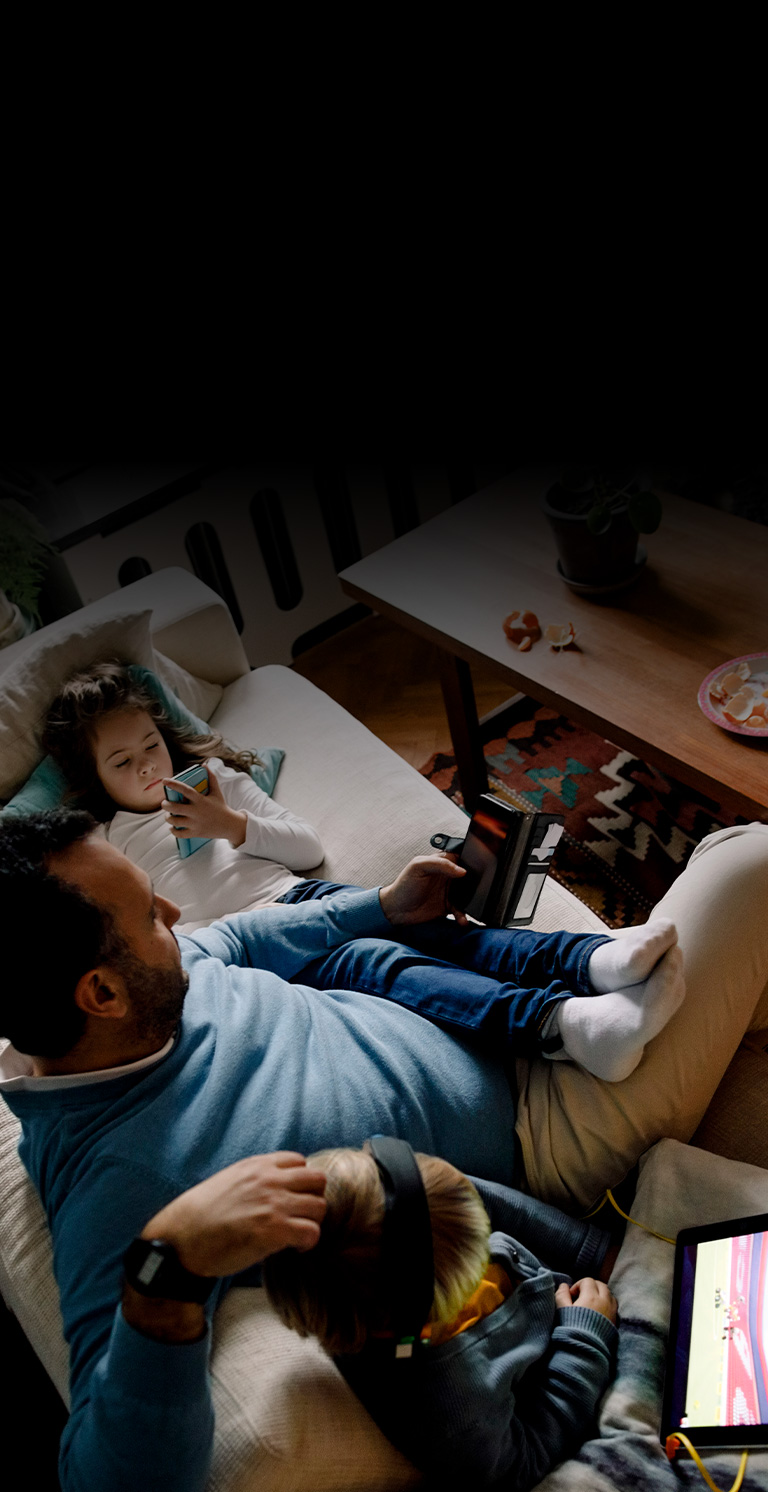 Family sitting on couch using mobile devices